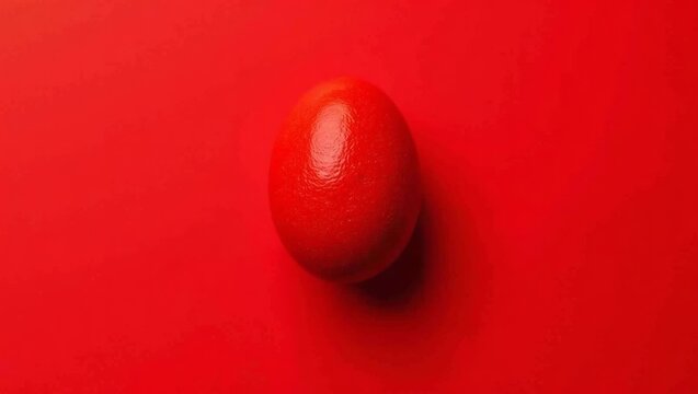 Single red egg placed on a vibrant red background, showcasing smooth texture and glossy finish, emphasizing color contrast and simplicity in design