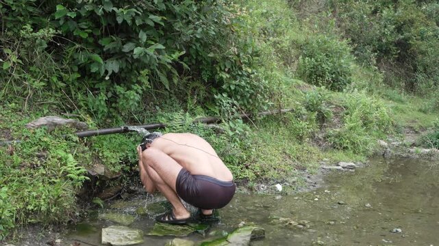 Unrecognizable Man Bathing in Natural Spring Water in the Middle of Forest