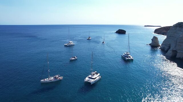 Sailboats float in Kleftiko bay in Milos island under a clear sky in the Mediterranean sea during daytime