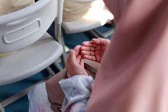 close-up view from behind the shoulder of a woman wearing a pink hijab, showing her open hands
