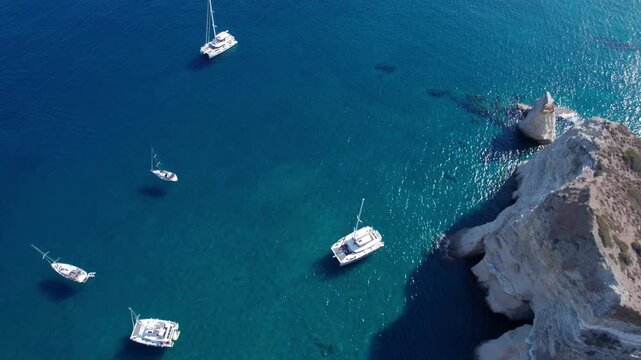 Sailboats navigate the clear waters of Kleftiko bay on Milos island in Greece during a sunny daytime aerial view