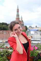 Fototapeta premium A beautiful blonde girl of European appearance stands and poses against the background of the Moscow Kremlin by the embankment