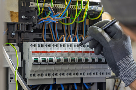 Utrecht, Netherlands - June 01, 2026: Close-up of an electrician using a marker to label new ABB circuit breakers inside a home electrical fuse box during installation.