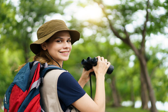 Young woman looking through binoculars during birdwatching in forest