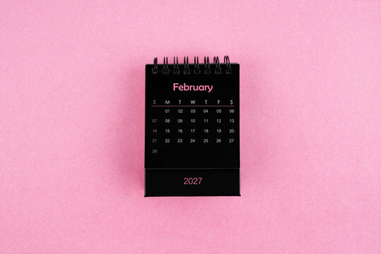 Black calendar for February 2027 year on pink color background.