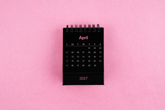 Black calendar for April 2027 year on pink color background.
