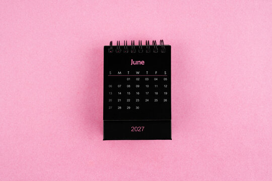 Black calendar for June 2027 year on pink color background.