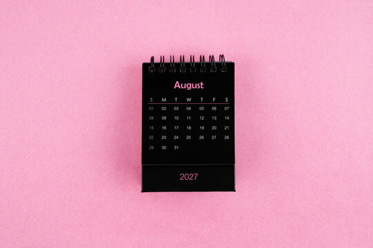 Black calendar for August 2027 year on pink color background.