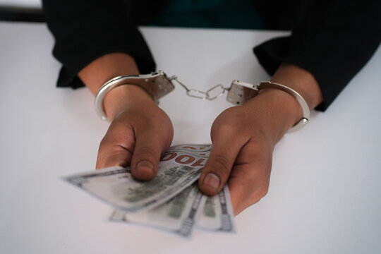 Handcuffed Hands Counting Banknotes: The Concept of Financial Crime and Illegal Money Transactions, Corruption or Bribery