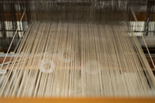 Close up abstract view of parallel threads stretched tightly on a traditional loom. Authentic Indonesian tenun textile weaving process.