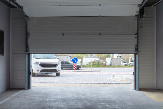 Partially open white automatic sectional garage door in underground parking