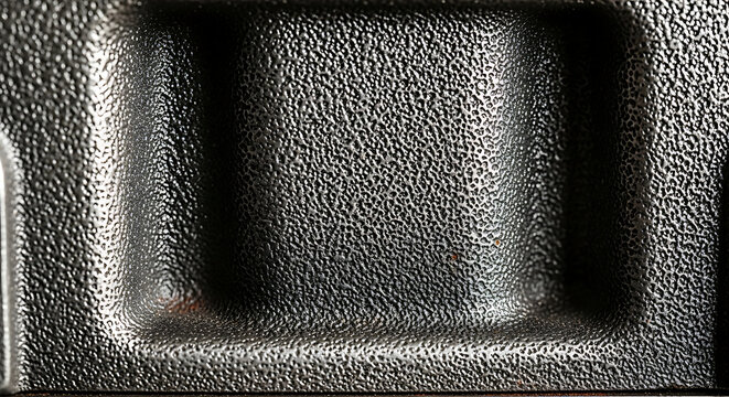 Black textured metallic surface with embossed rectangular panel detail, material