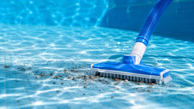 Blue pool vacuum cleaner on the bottom of a swimming pool removing debris and leaves