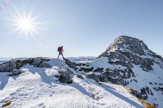 Climbers on the rocky summit ridge with first snow in autumn, hiking trail to Guffert, solar reflex, Brandenberg Alps, Tyrol, Austria