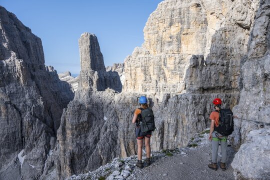 Mountaineers look at Campanile Alto pinnacle, Bocchette Centrale band trail, via ferrata in the Brenta Mountains, Parco Naturale Brenta-Adamello, Trentino, Italy