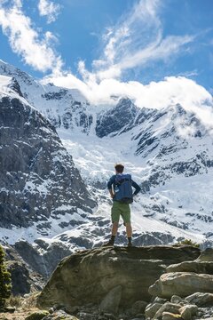 Mountaineer stands on rocks, impressive view of Rob Roy Glacier, Mount Aspiring National Park, Otago, South Island, New Zealand