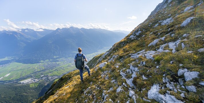 Hiker on hiking trail, Inn valley and mountain panorama in the background, descent from Hohe Munde, Mieminger Kette, Tyrol, Austria