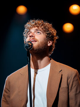 Male vocalist captivating the audience on stage with a spotlight shining bright and a microphone in hand during an electrifying live music performance