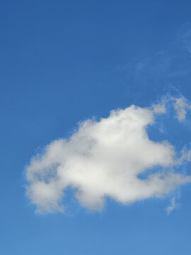 Single Fluffy White Cloud Floating in Clear Blue Sky