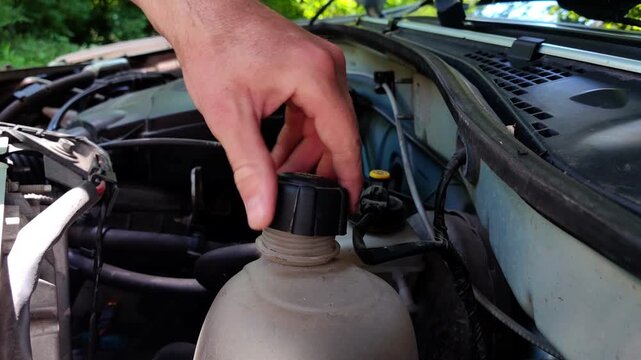 Closing coolant reservoir cap during car maintenance, vehicle service procedure, engine care, automotive reliability.