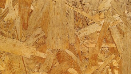 Pressed OSB Board showing chaotic patterns of compressed wooden flakes. Suitable for raw construction material catalogs, DIY carpentry blogs, and industrial interior designs. © Tapasii
