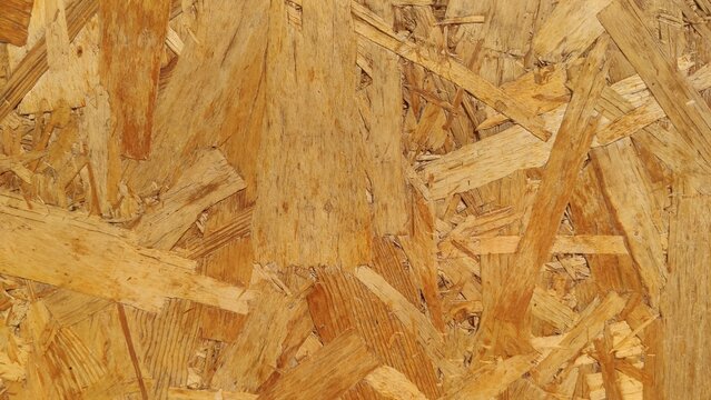 Pressed OSB Board showing chaotic patterns of compressed wooden flakes. Suitable for raw construction material catalogs, DIY carpentry blogs, and industrial interior designs.