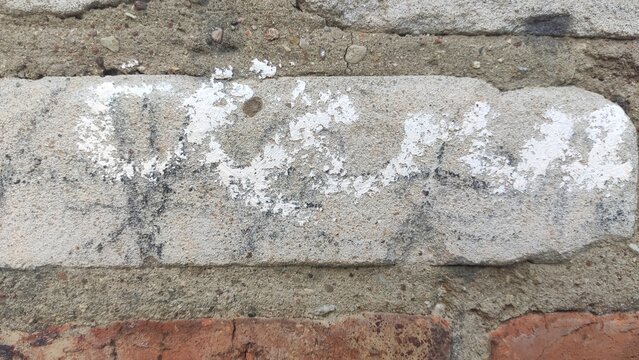 Messy Cement Pointing covering a single red block in an old masonry structure. Ideal for DIY home repair fails, historic building restoration, and heavy urban textures.