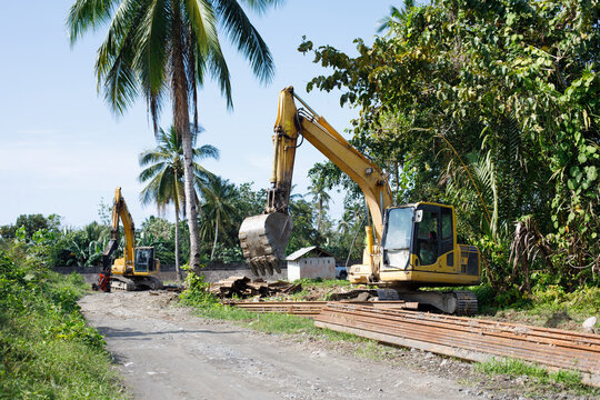 Construction machinery working in tropical environment with palm trees, Philippines infrastructure development