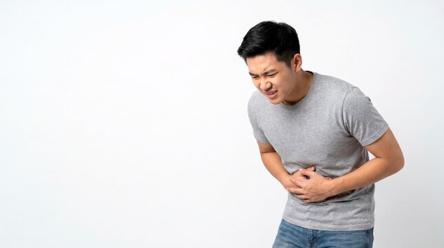 Asian Man Suffering from Severe Stomach Pain or Gastritis Against White Background