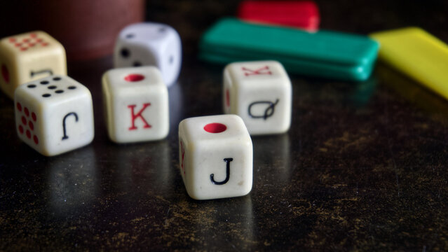 Poker dice on a dark surface, representing chance, leisure, and entertainment