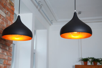 Close-up of two black lamps with yellow glow in the kitchen © Svitlana