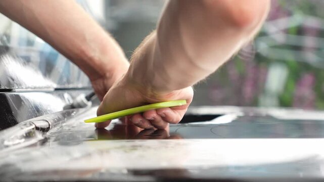 Car wrapping, detailing, tuning and styling. Selective focus. PPF protective film against chips and scratches. A car wrapping specialist applies a polyurethane film to the car. Detailer smoothes PPF. 