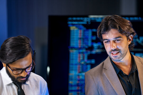 Diverse AI team members in name badges review robotic and semiconductor components at a technology exhibition at night.