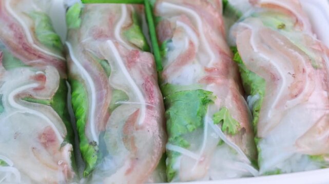 Freshly made vietnamese spring rolls filled with pork, vermicelli, and vegetables rotating on a platter. This healthy and authentic asian appetizer is a popular dish from southeast asia