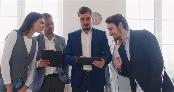 Business team meeting during corporate training session. People align strategy and responsibilities while reviewing notes on tablets in modern office. Clear collaboration, leadership at work.