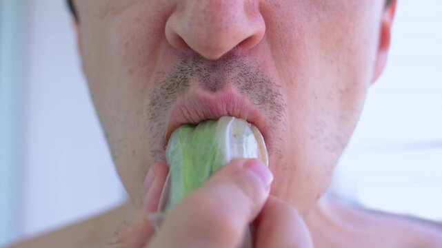 Close up of a man's lower face showing him eagerly biting into and chewing a fresh vietnamese spring roll, highlighting the details of his mouth and the texture of the rice paper wrap