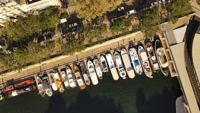 Aerial view of moored houseboats and pleasure crafts along the Seine riverbank in Paris, Ile-de-France, France.