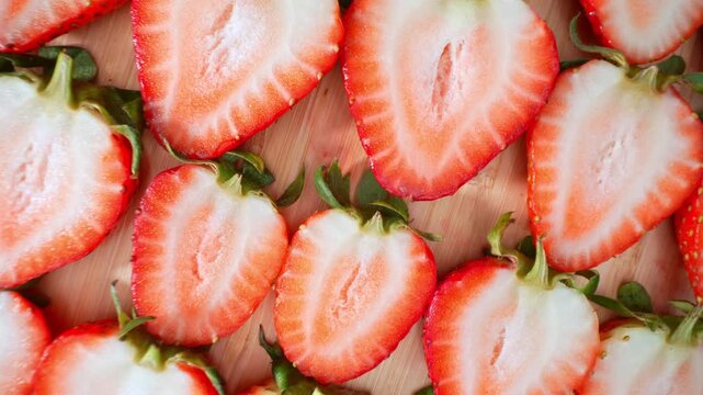 Top view of sliced strawberries showcases vibrant red edges and pale centers, perfect for concepts of organic farming, antioxidant-rich fruits, wholesome diets, and seasonal harvests. 4k.

