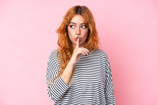 Young caucasian woman isolated on pink background showing a sign of silence gesture putting finger in mouth