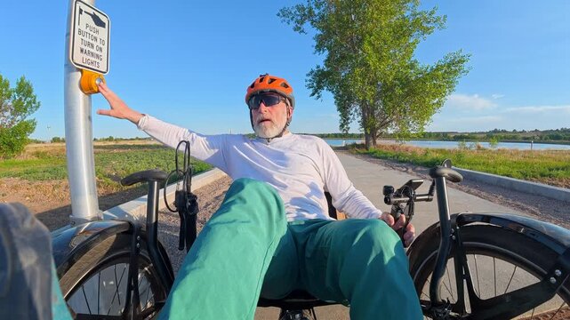 Senior cyclist is riding a full suspension recumbent tricycle on a bike trail in northern Colorado and crossing a highway - Kyger Open Space