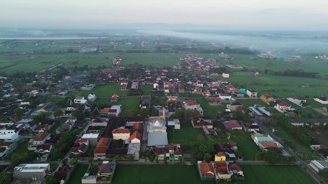 Drone aerial view of Karanganyar, a small town in Central Java, Indonesia, during a peaceful morning with warm sunrise light illuminating the urban landscape and residential neighborhoods.