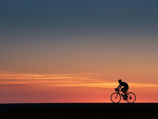 Fototapeta premium Silhouette of Person Cycling on a Road during Vibrant Sunset Sky