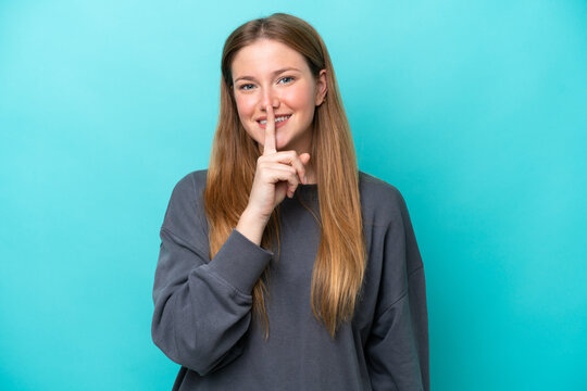 Young caucasian woman isolated on blue background showing a sign of silence gesture putting finger in mouth