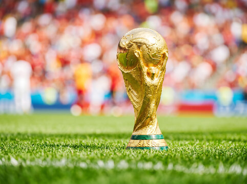 Fifa world cup trophy on grass with blurred stadium crowd