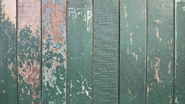 Vintage green peeling paint wooden plank texture. Distressed dark green vertical wooden boards texture. Close-up of a grunge green vertical wood planks background with scratches and weathering.