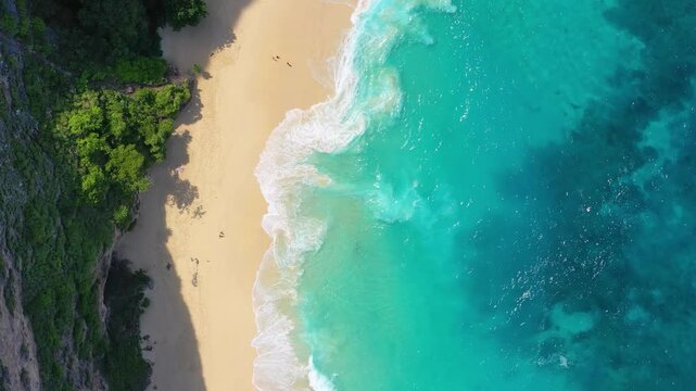 Aerial top down view of big ocean waves crashing on a sandy beach. Nature background with sea surf foam for summer vacation and travel concepts.