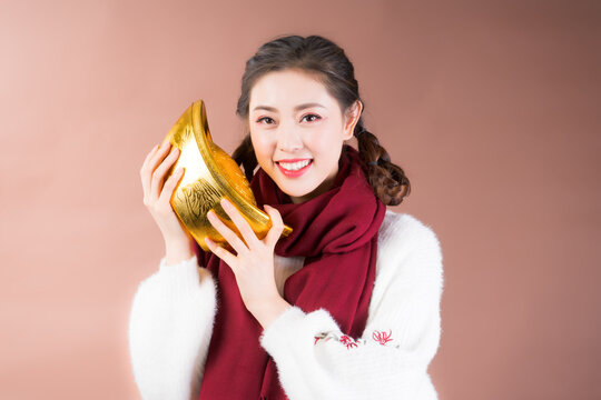 Smiling woman holding traditional gold sycee symbol of prosperity