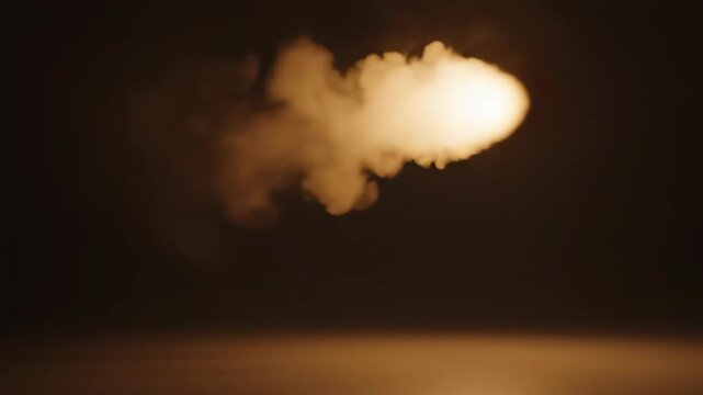 A glowing orange smoke effect or vape cloud illuminated against a dark background, creating a dramatic visual atmosphere