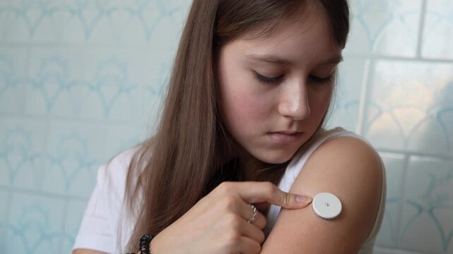Measurement of blood glucose with the help of mobile applications and sensors. young girl approaches the cell phone to the sensor located in the patch on her arm.