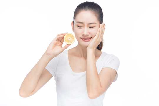 Young woman with tooth sensitivity holding lemon slice and touching cheek